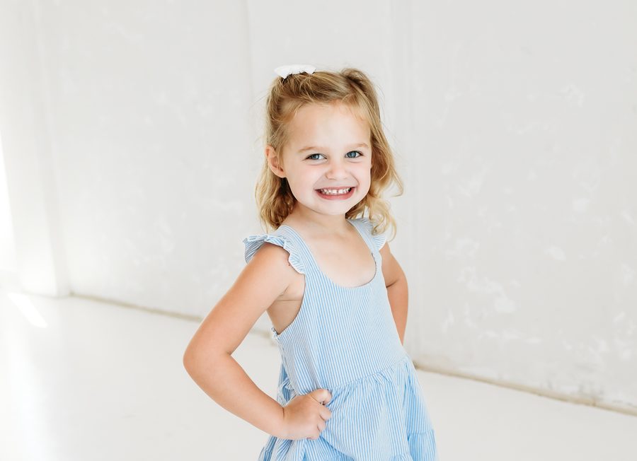 A girl in a pale blue dress with her hand on her hip