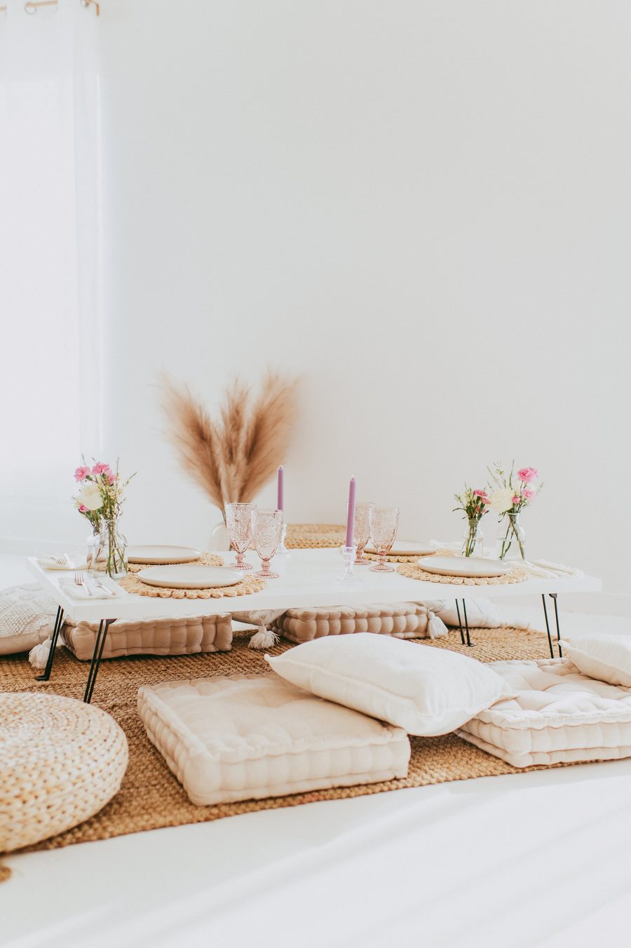 Floor cushions around a low table with pampas grass