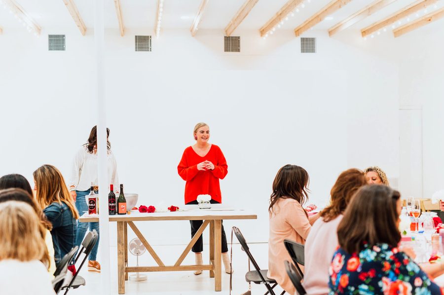 A host speaking to guests seated at workshop tables in the Edmond studio