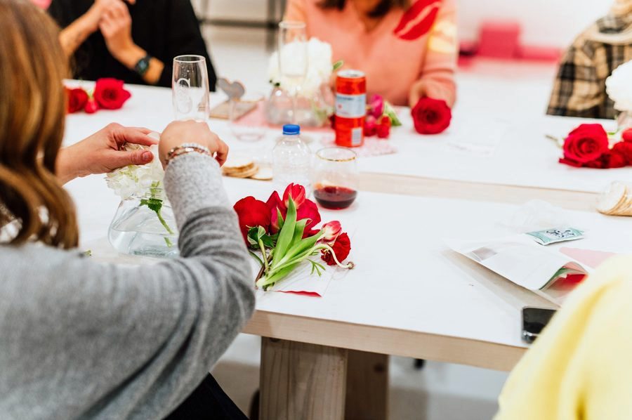 Guests arranging red roses at a workshop table