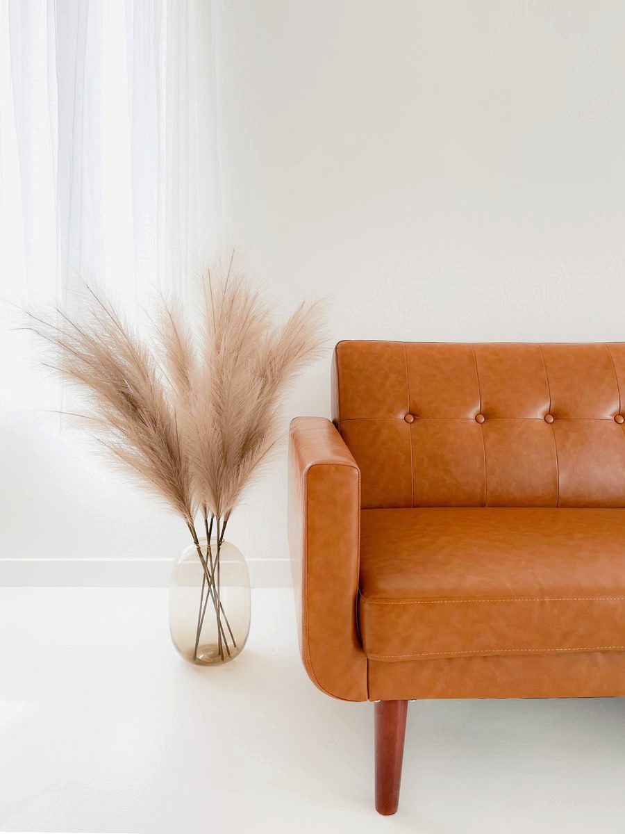 A tan leather chair beside dried pampas grass