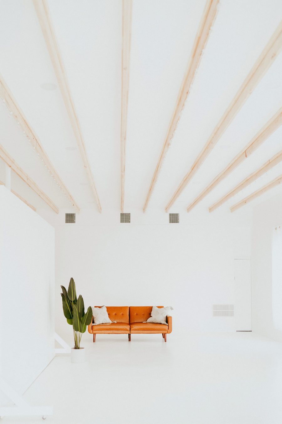 Timber beams over the white room and its leather sofa